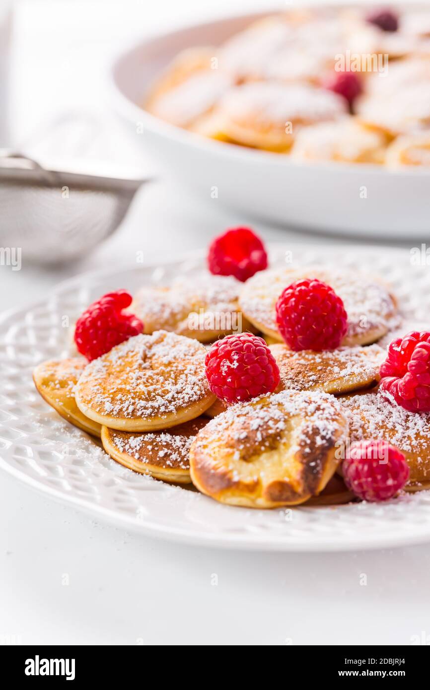 Poffertjes - small Dutch pancakes with fresh raspberries. Traditional Dutch cuisine. Stock Photo
