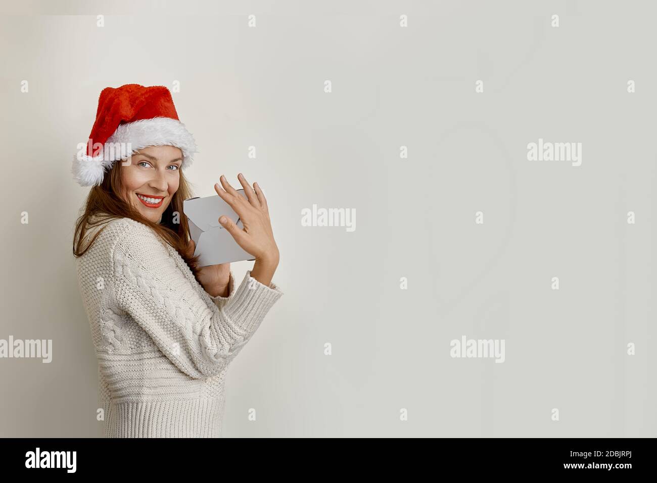 Portrait of beautiful young woman in santa hat holding paper bags Stock Photo