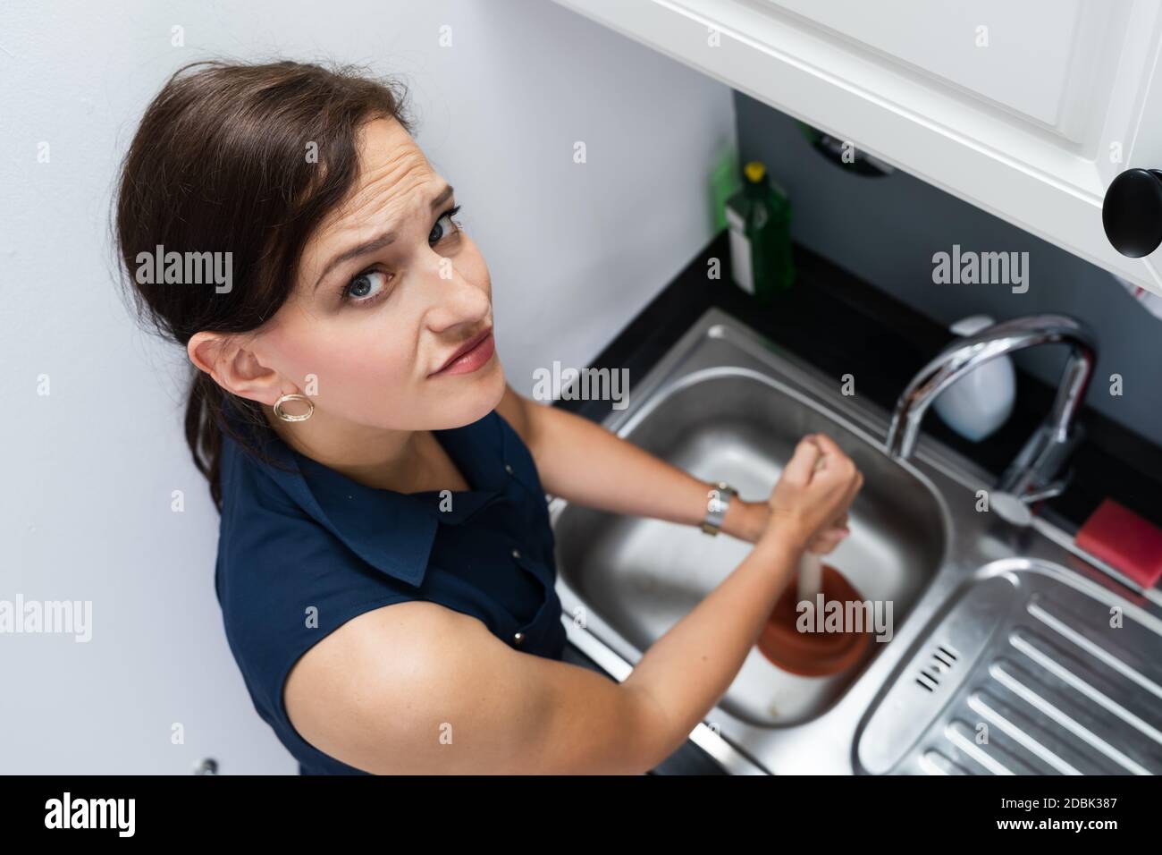 Cleaning Blocked Sink And Drain In Kitchen Using Plunger Stock Photo