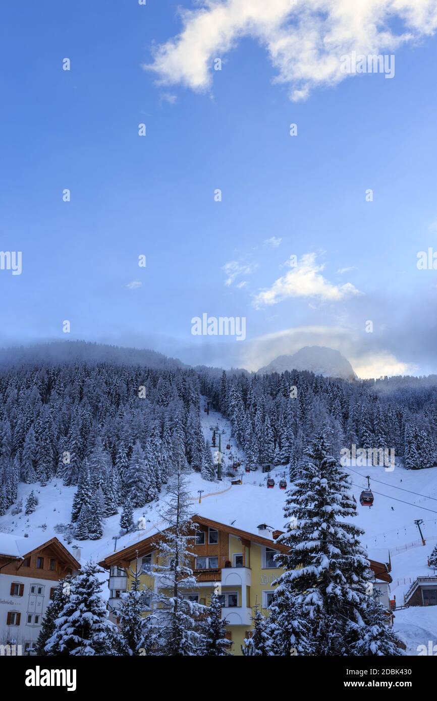 Tyrolean house in Val Gardena with ski lift behind in winter, Dolomites