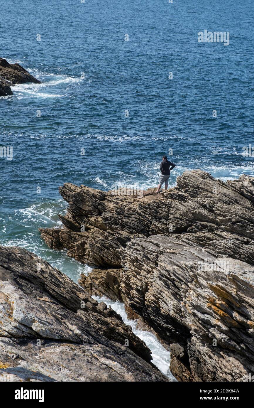 Man fishing on the rocks at The Cote Sauvage on The Quiberon Peninsula, Brittany, France. Stock Photo