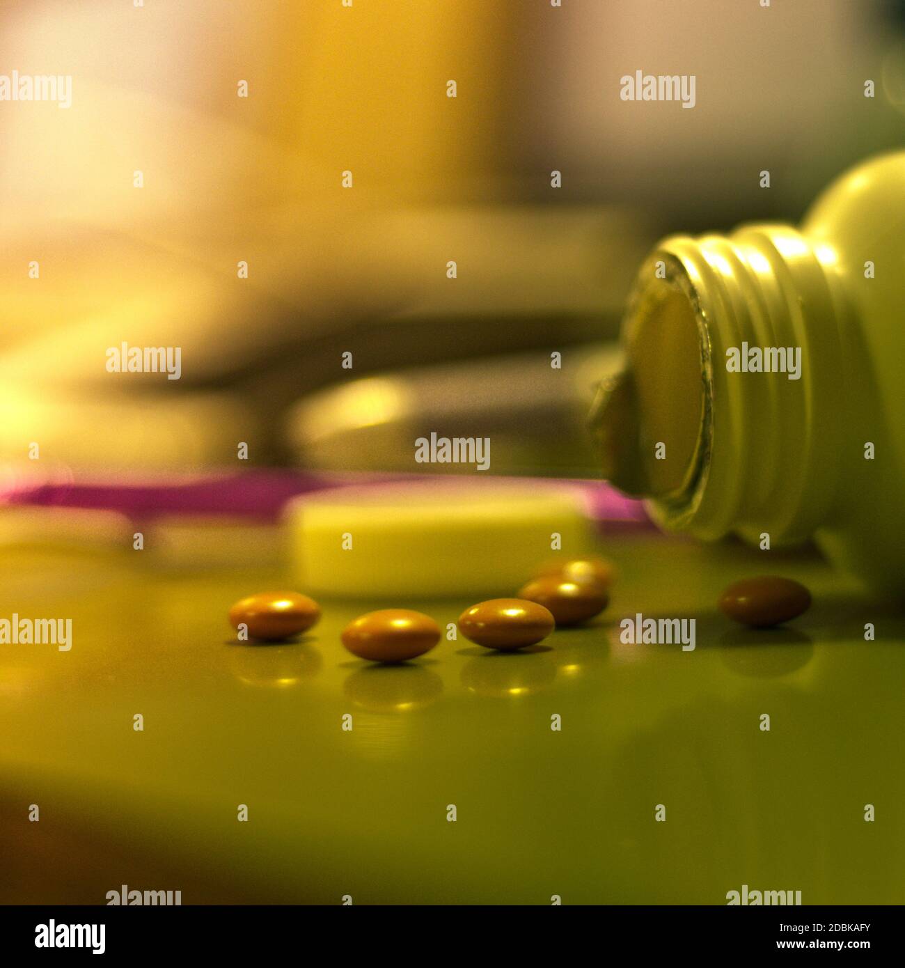 An open bottle of pills spills out onto a shiny table Stock Photo