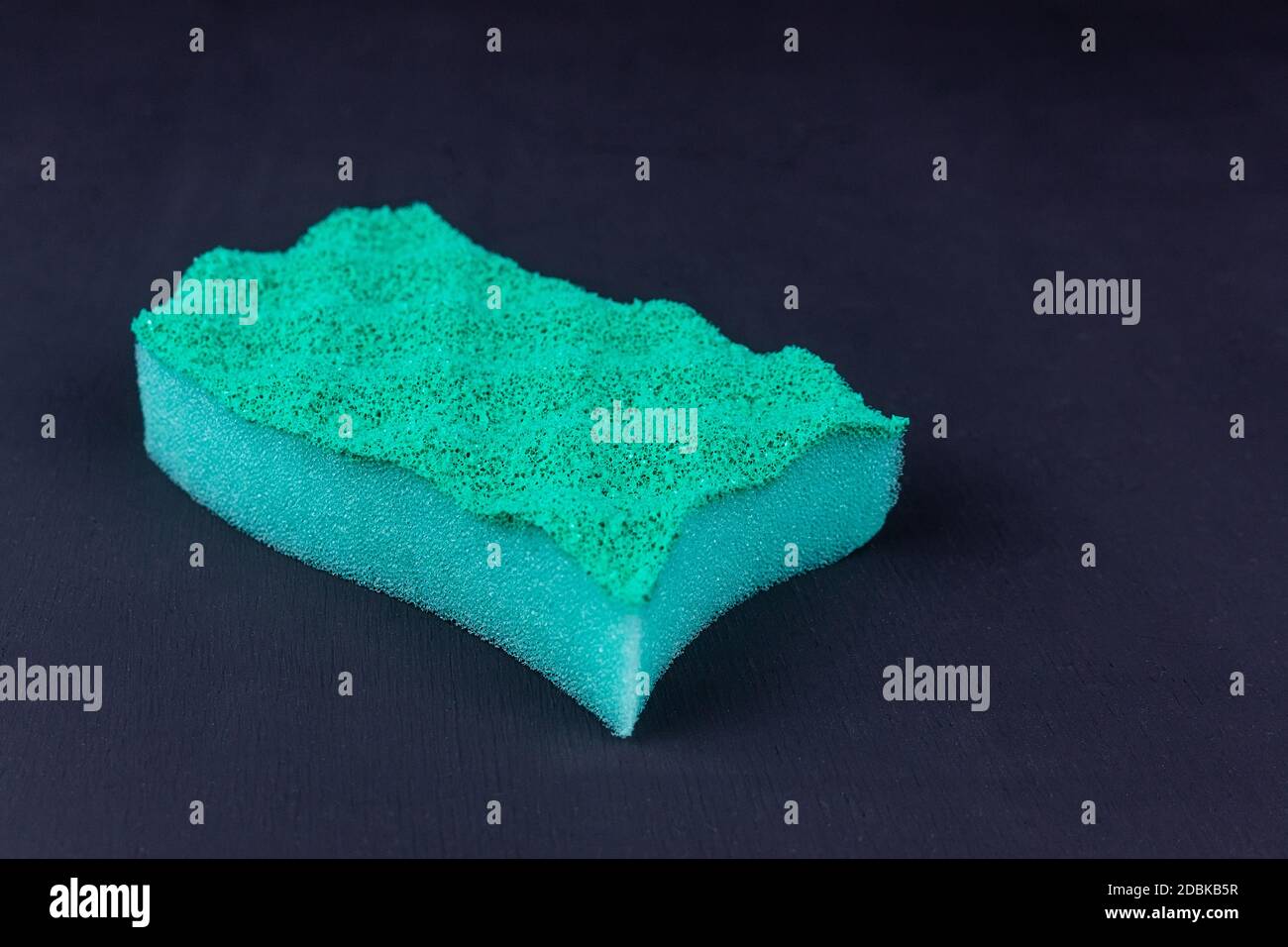 green kitchen sponge on a black background in different poses. Scrub