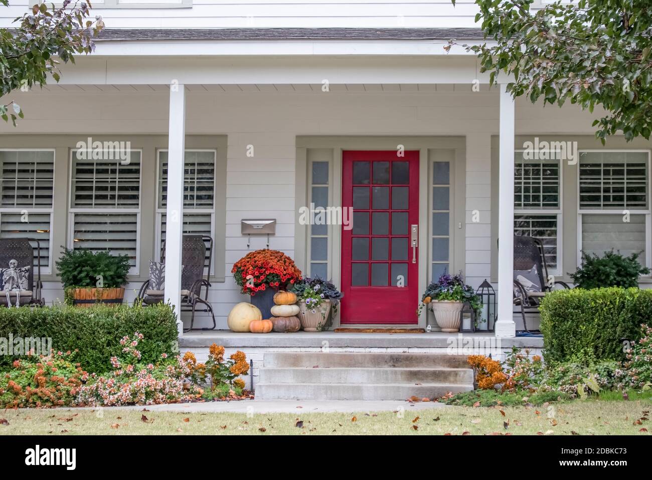 Entrance and porch to pretty house with Autumn and Halloween decorations and fall leaves blowing in the wind - curb appeal Stock Photo