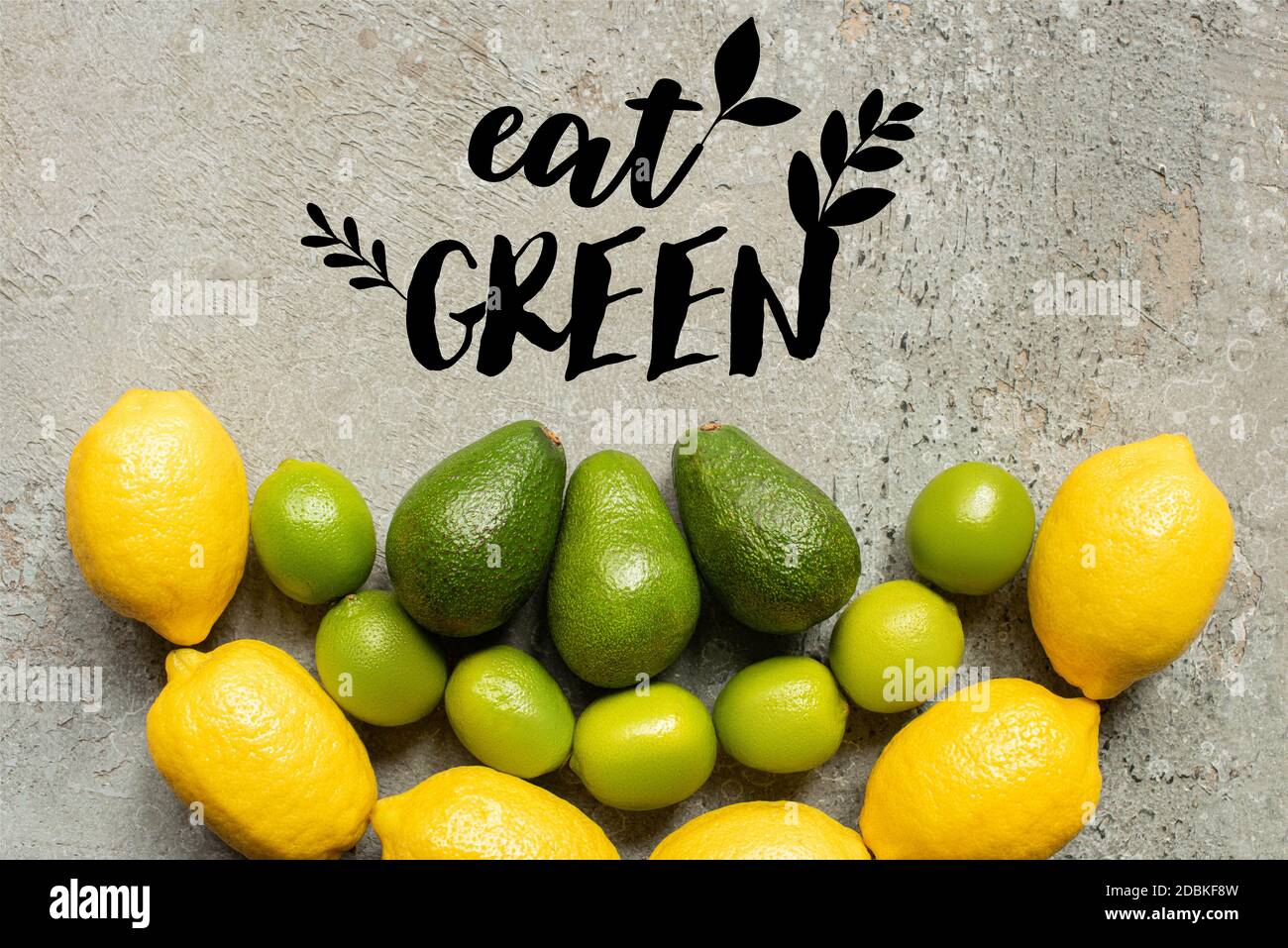 top view of colorful avocado, limes and lemons on grey concrete surface