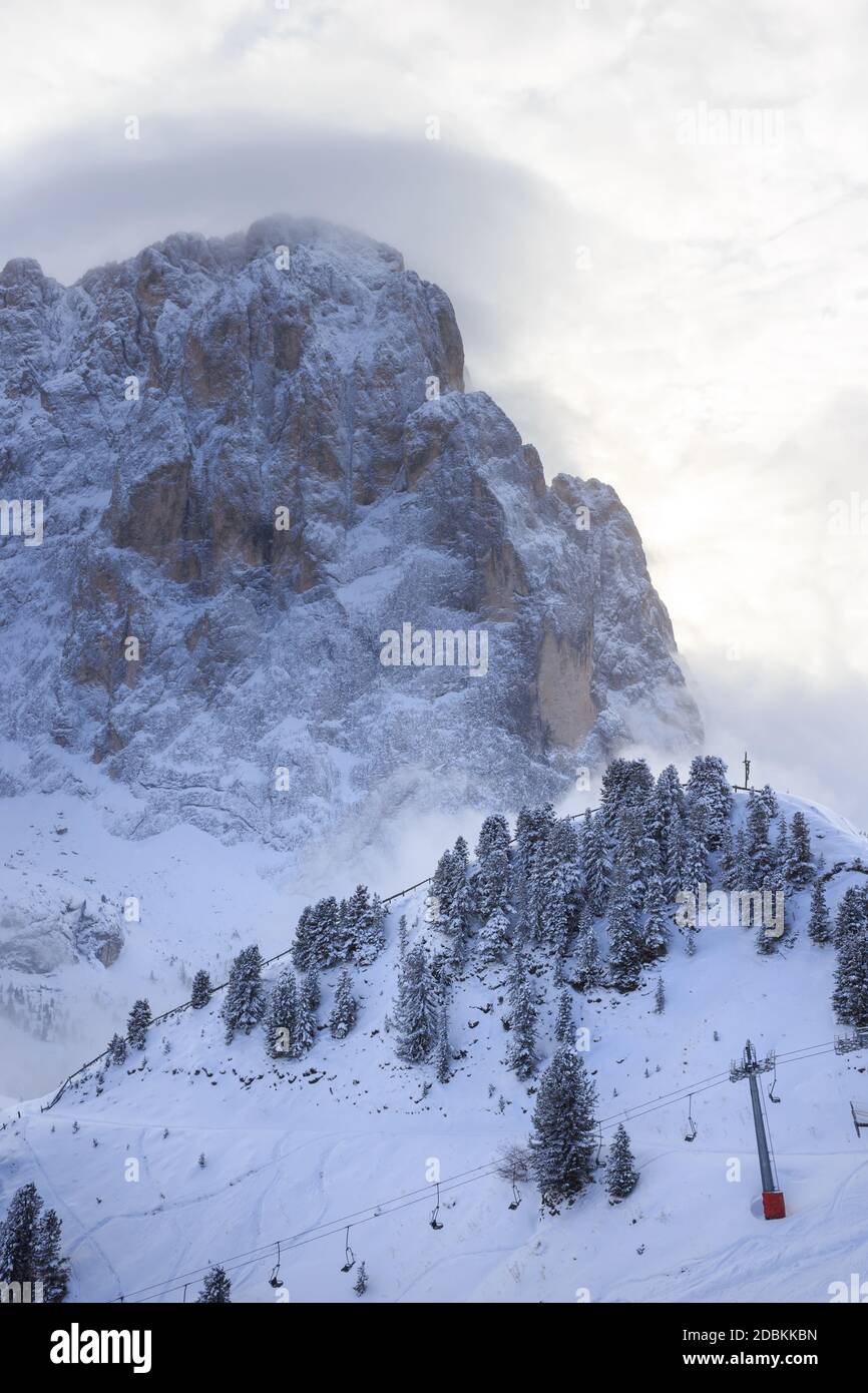 Part view of the Sassolungo mountain and ski lift in winter, with some clouds behind, Val Gardena, Italy Stock Photo