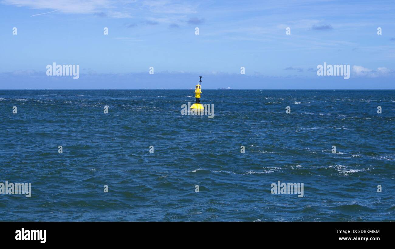 Gelbe Sicherheits-Boje schwimmt in der rauen Nordsee vor Horizont und blauem Himmel Stock Photo