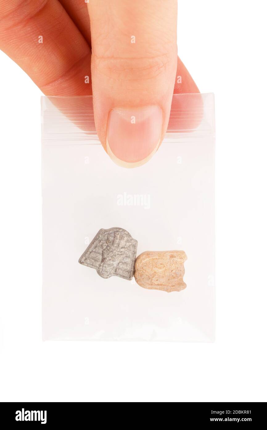 Ecstasy pills in plastic bag in dealers hand isolated over white. Stock Photo