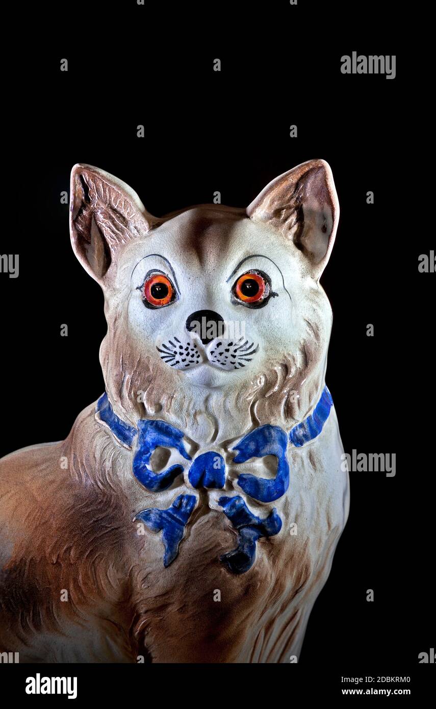 Ceramic domestic cat ornament close up looking at camera on black background Stock Photo