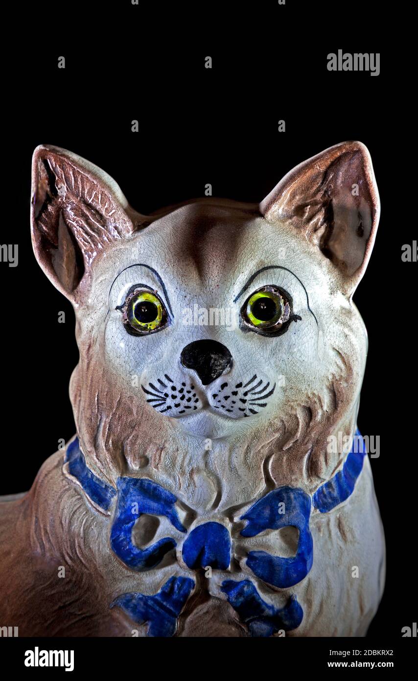 Ceramic domestic cat ornament close up looking at camera on black background Stock Photo