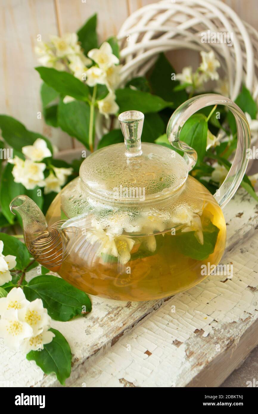 green tea with jasmine in glass teapot on wooden shabby table, vertical