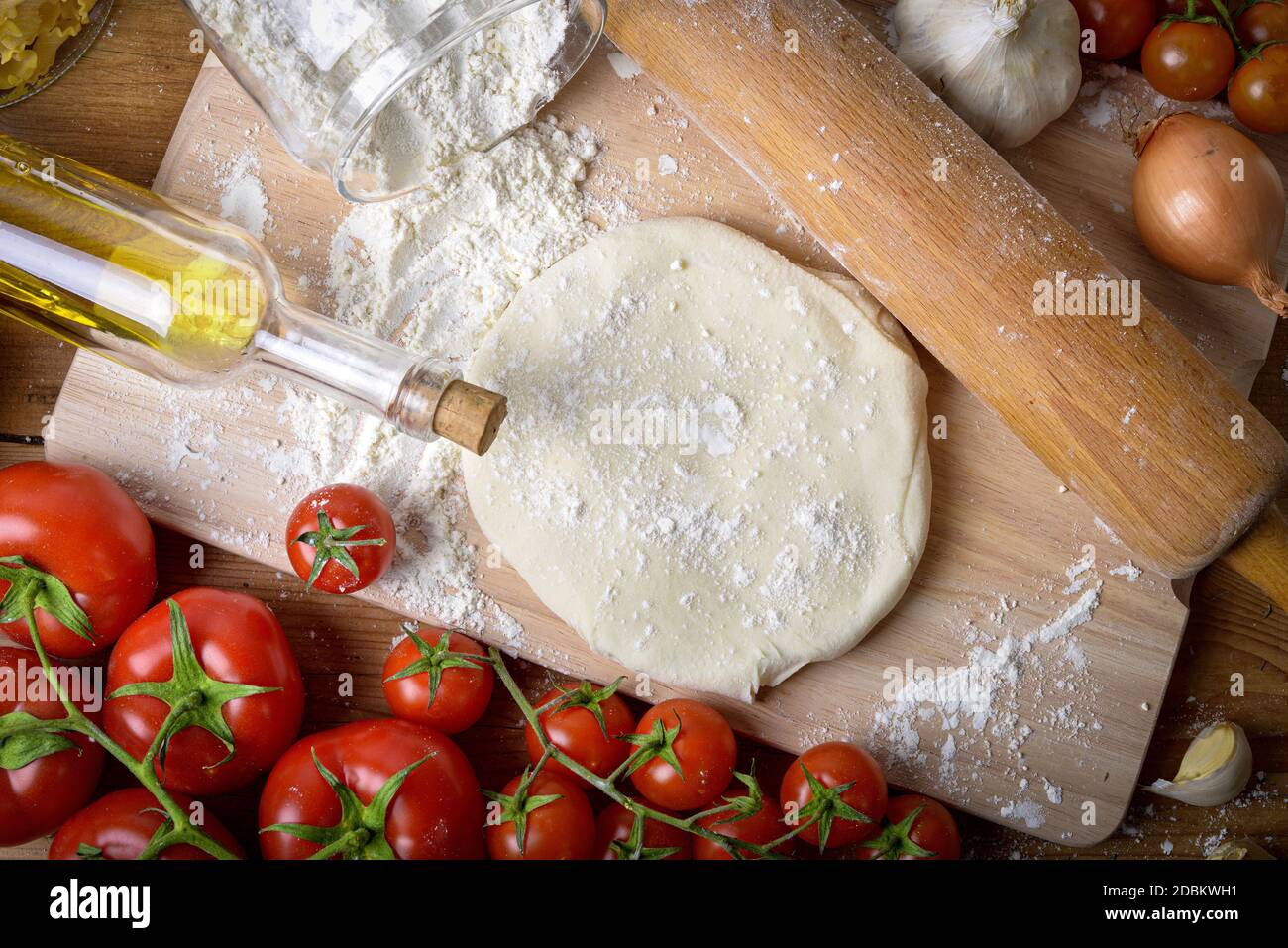 an homemade pizza dough with onions and fresh tomatoes Stock Photo