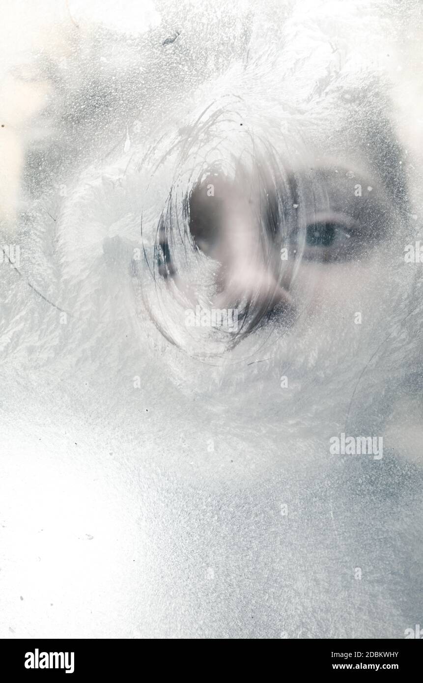 adorable little child face looking through frosty icy window Stock Photo