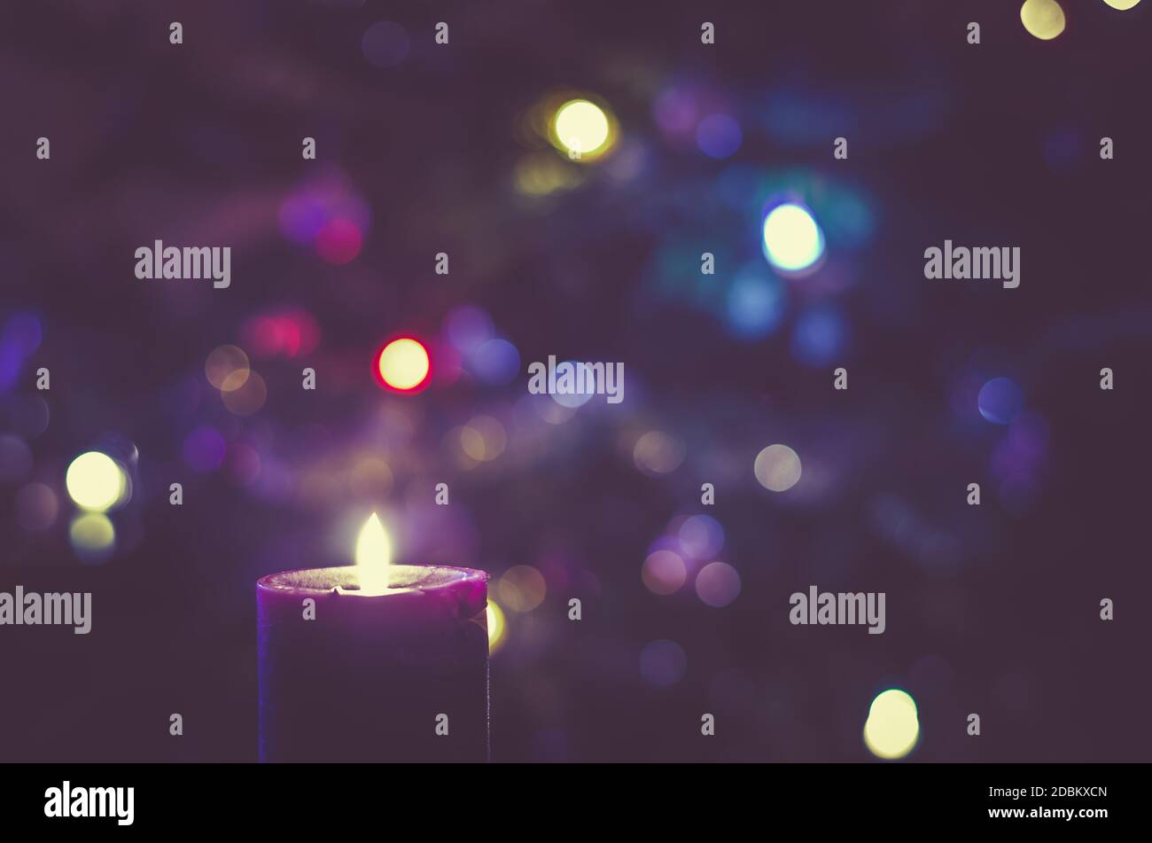 one burning candle concept with shining bokeh glittering ligts on christmas tree on background Stock Photo