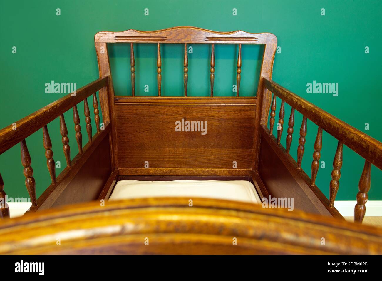 Antique retro wooden baby crib in babies room with green walls modern interior close-up Stock Photo