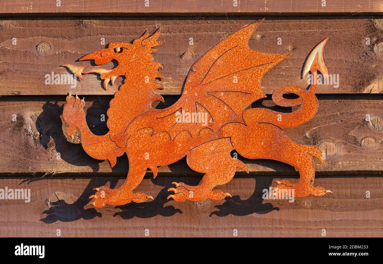 Rusty Stamped Metal Sculpture On A Wooden Fence Of The Passant Welsh Red Dragon, Y Ddraig Goch, The Symbol On The National Flag Of Wales Stock Photo