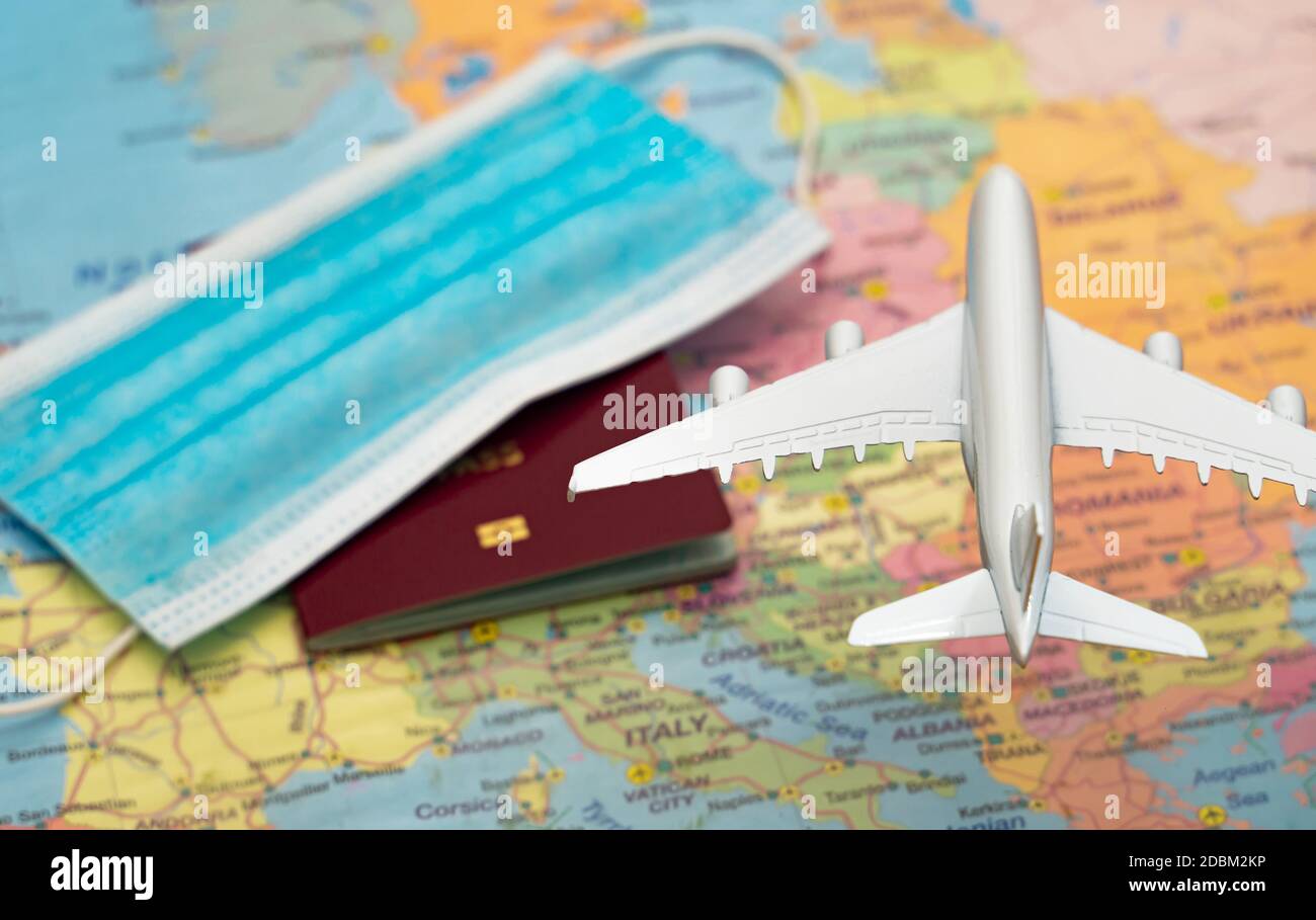 Toy of a plane, medical mask and passport on the Europe map. Stock Photo