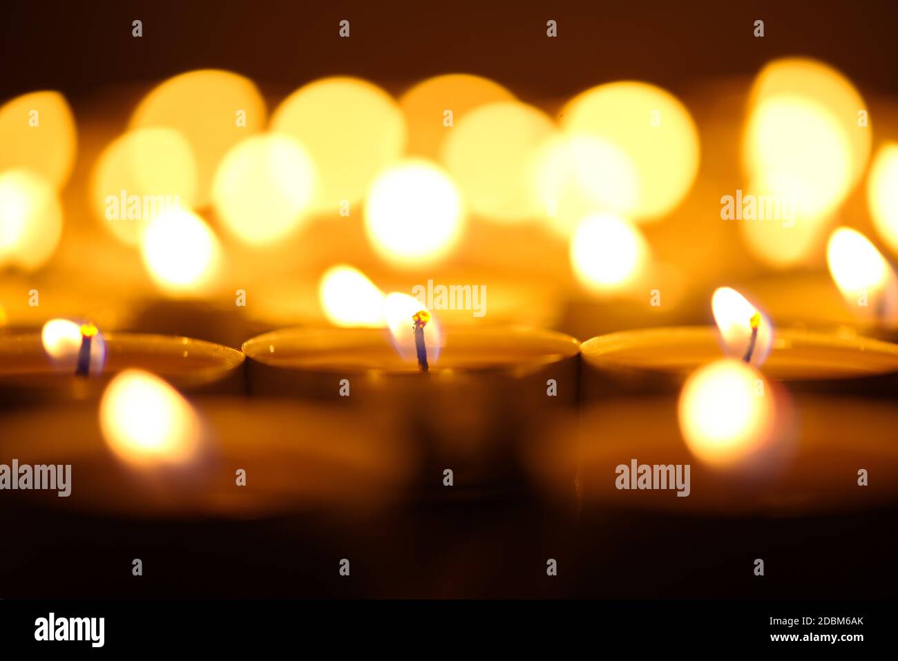 Burning candles. Shallow depth of field. Many christmas candles burning at night. Abstract candles background. Many candle flames glowing on dark back Stock Photo