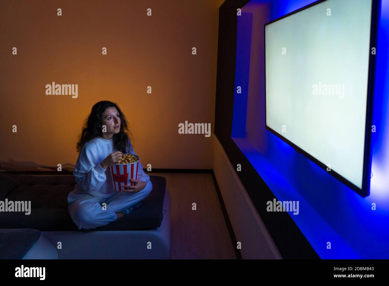 person watches a movie sitting on the couch with a bucket of popcorn Stock  Photo - Alamy