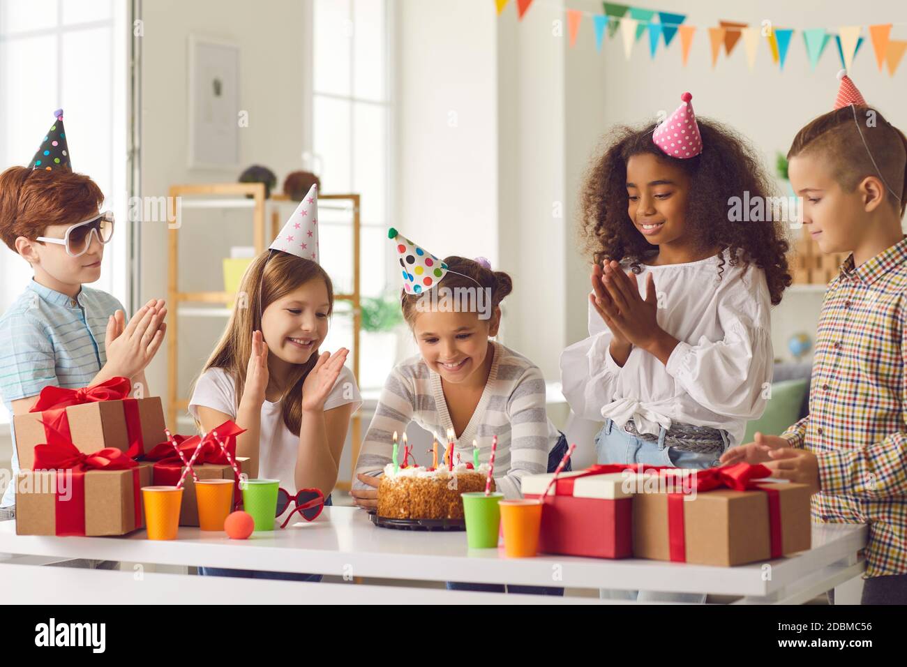 Happy girl making her birthday wish before blowing candles on cake