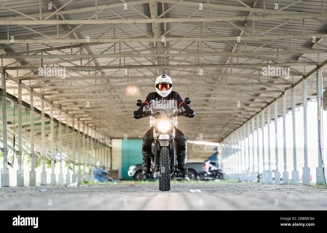Man riding his off road motorbike through empty warehouse in Bangkok Stock Photo