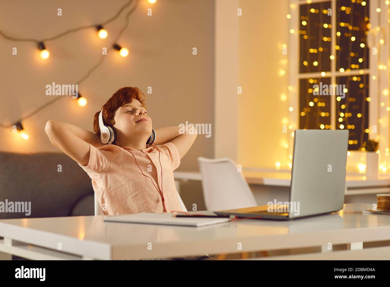 Calm boy with closed eyes listens to music in headphones in front of