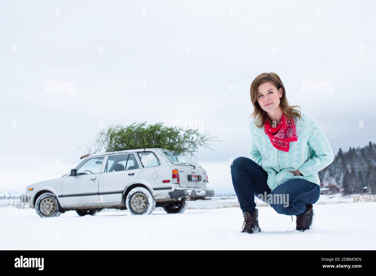Portrait of woman in winter scene with tiny car and christmas tree Stock Photo