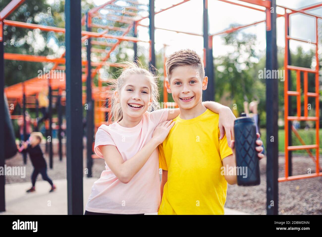 Teens children and sports theme. Two kids athletes twins rest and replenish their thirst during workout outdoor gym workout in sunny summer weather. S Stock Photo