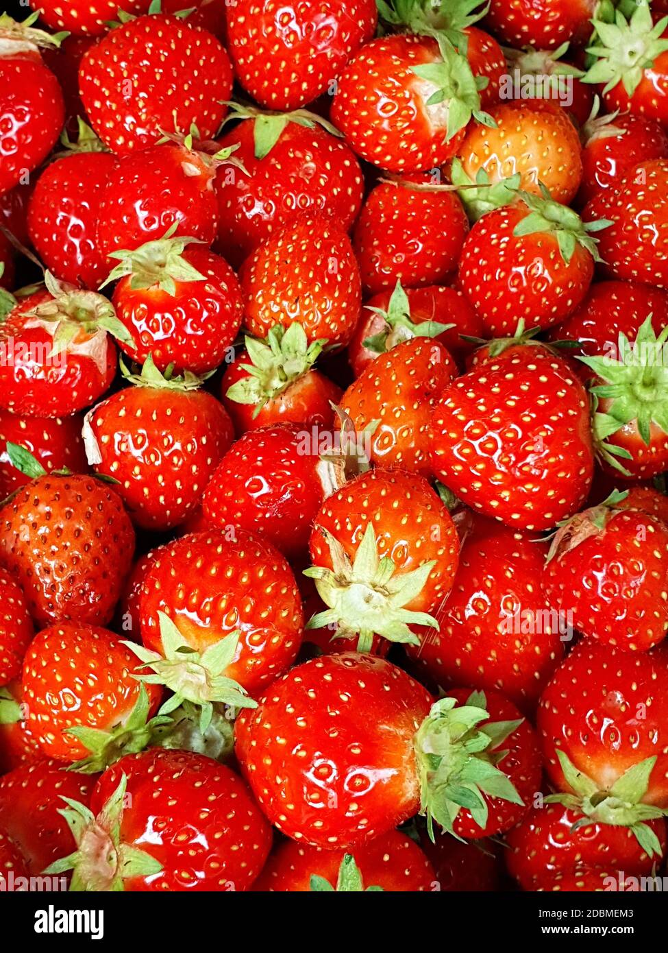 Full frame background with fresh whole strawberries with green leaves ...