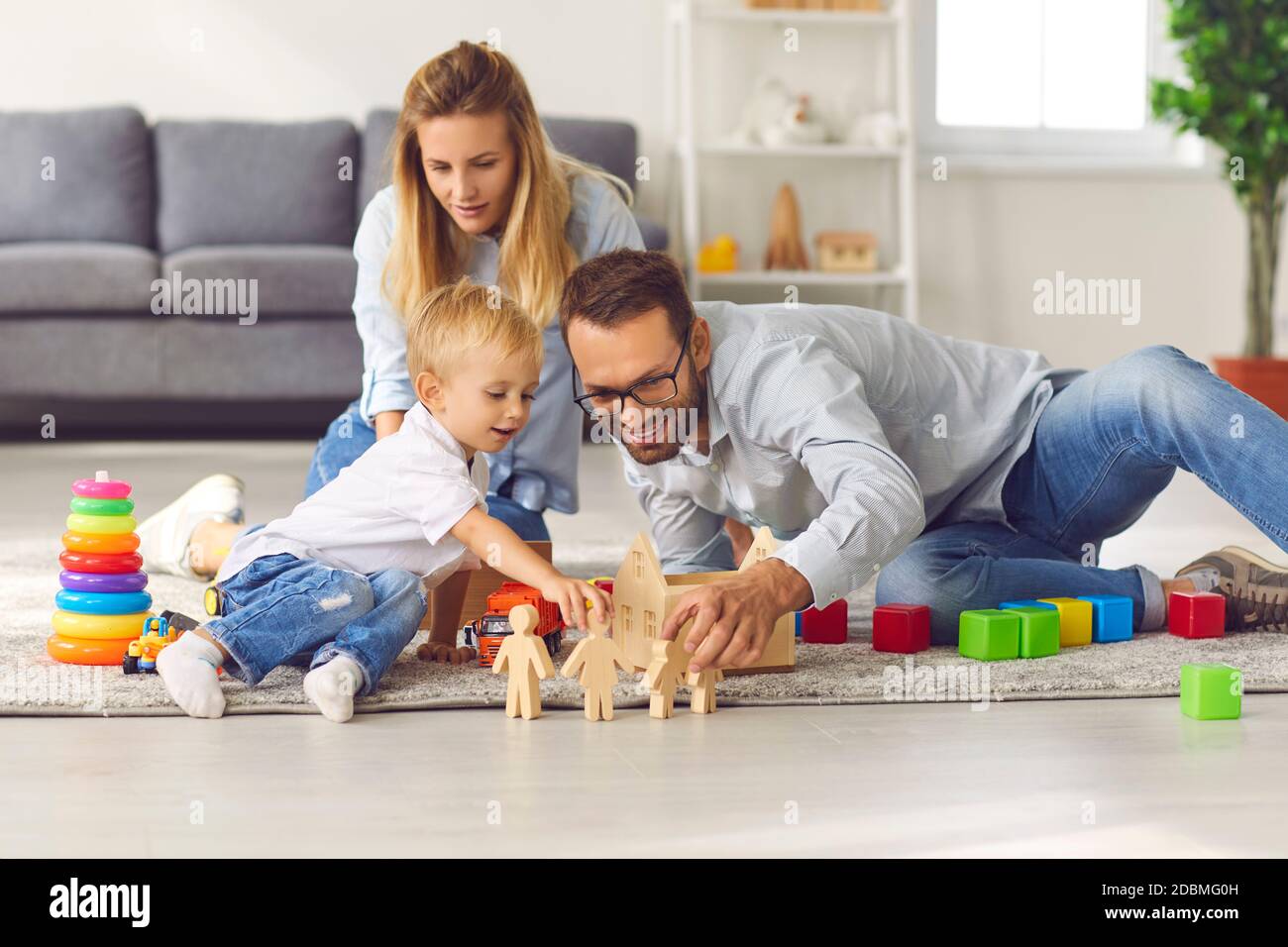 Happy family playing with toys on floor of their living-room, enjoying quality time at home Stock Photo