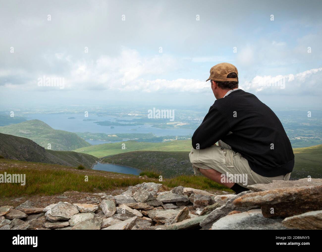 Lone male hiker admires the view over the Lakes of Killarney and the valley from Mangerton mountain in Killarney National Park, County Kerry, Ireland Stock Photo