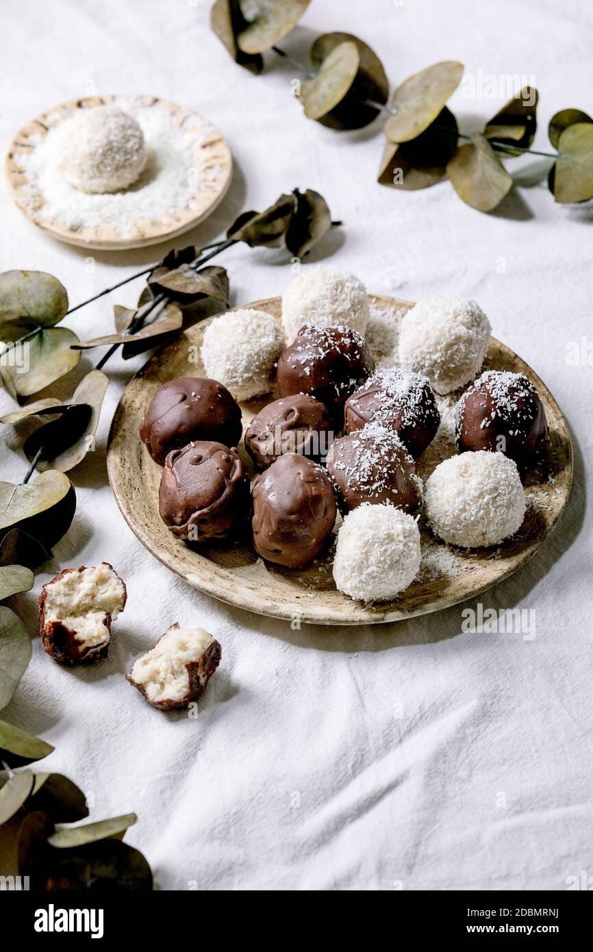 Raw vegan coconut chocolate candy balls over white with eucalyptus