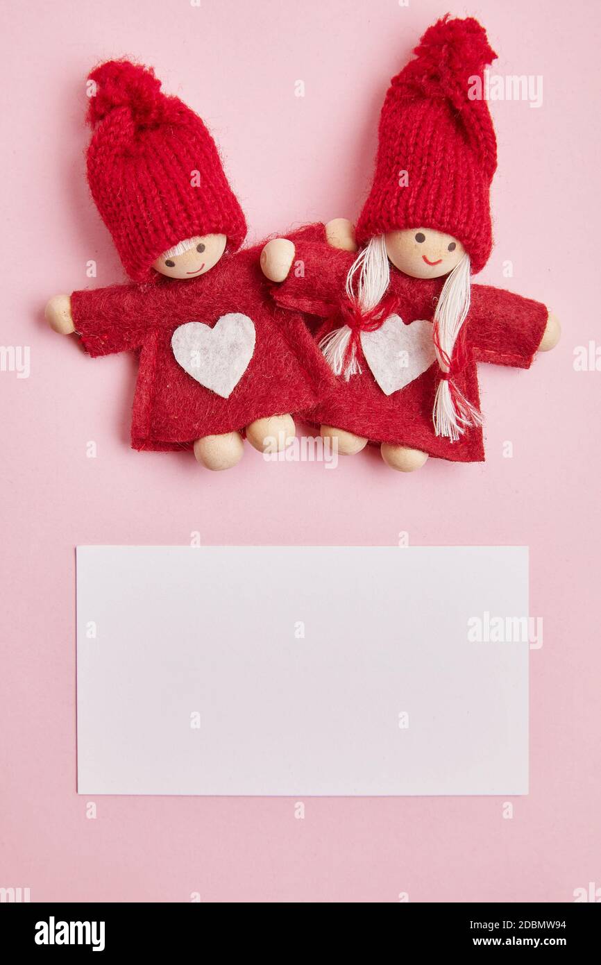 Toy midgets with greeting card on the rose background Stock Photo