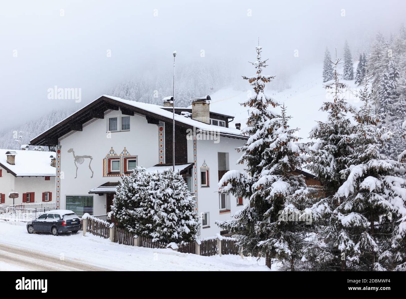 Street view with traditional hotel, car with fresh snow on an overcast day, Selva Gardena, Dolomites, Italy Stock Photo