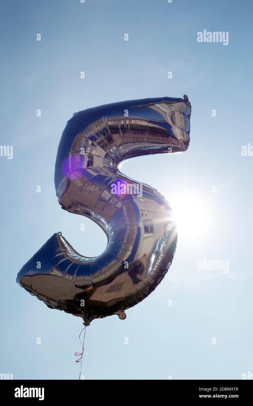 number 5 helium filled balloon against a blue sky Stock Photo