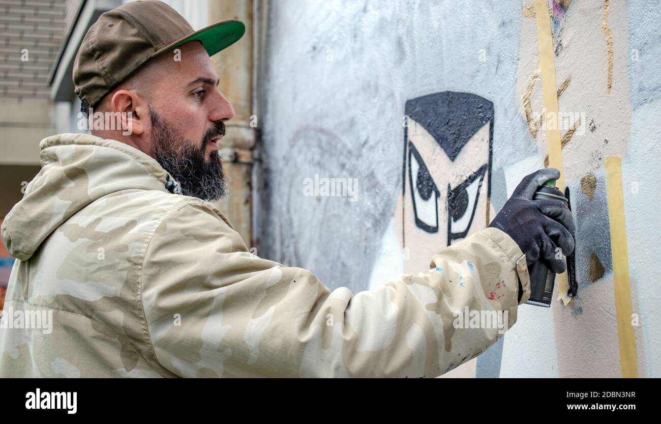 Graffiti artist in action, painting on the wall with aerosol spray