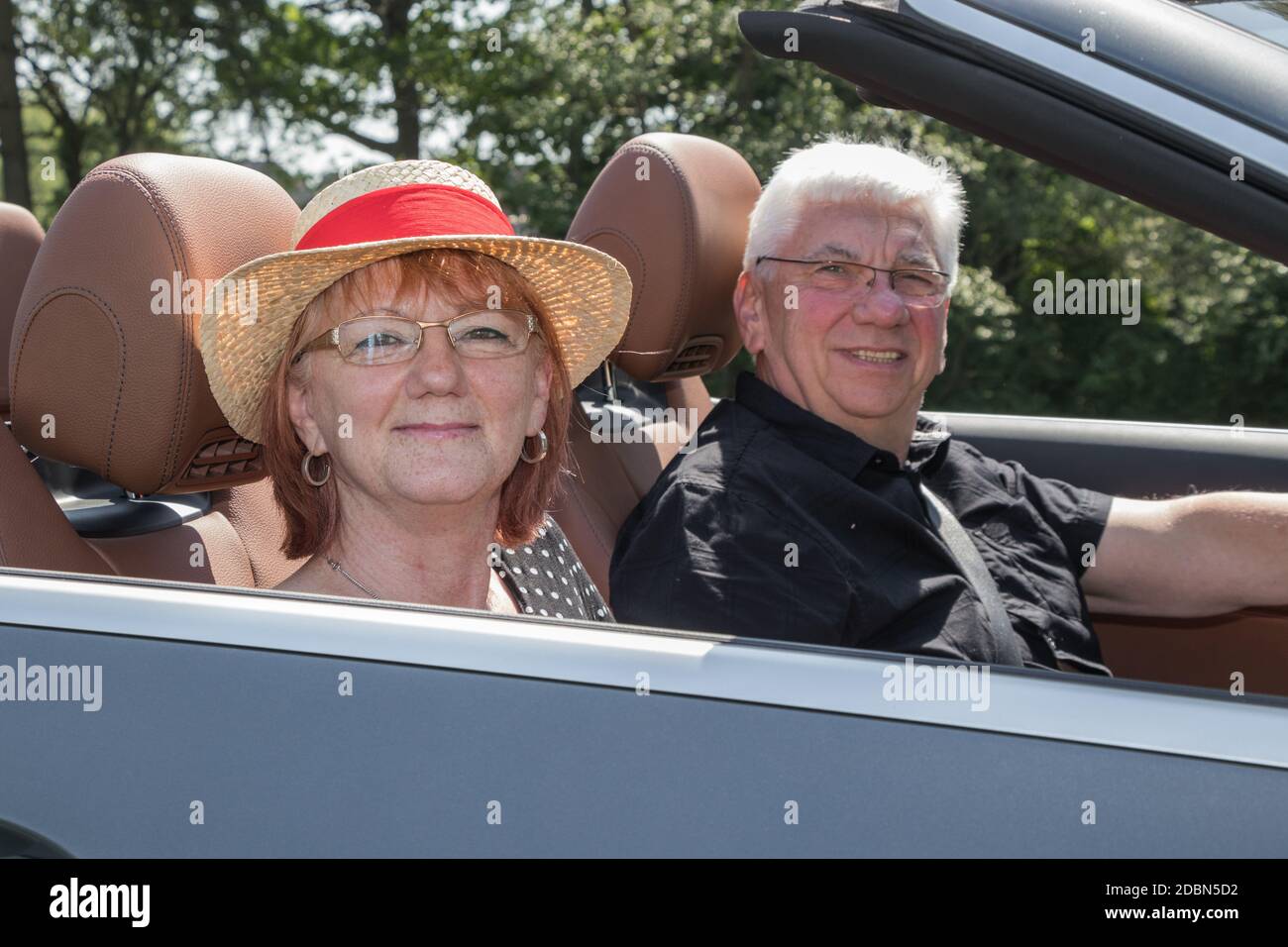 Older couple drives with a luxury convertible car Stock Photo