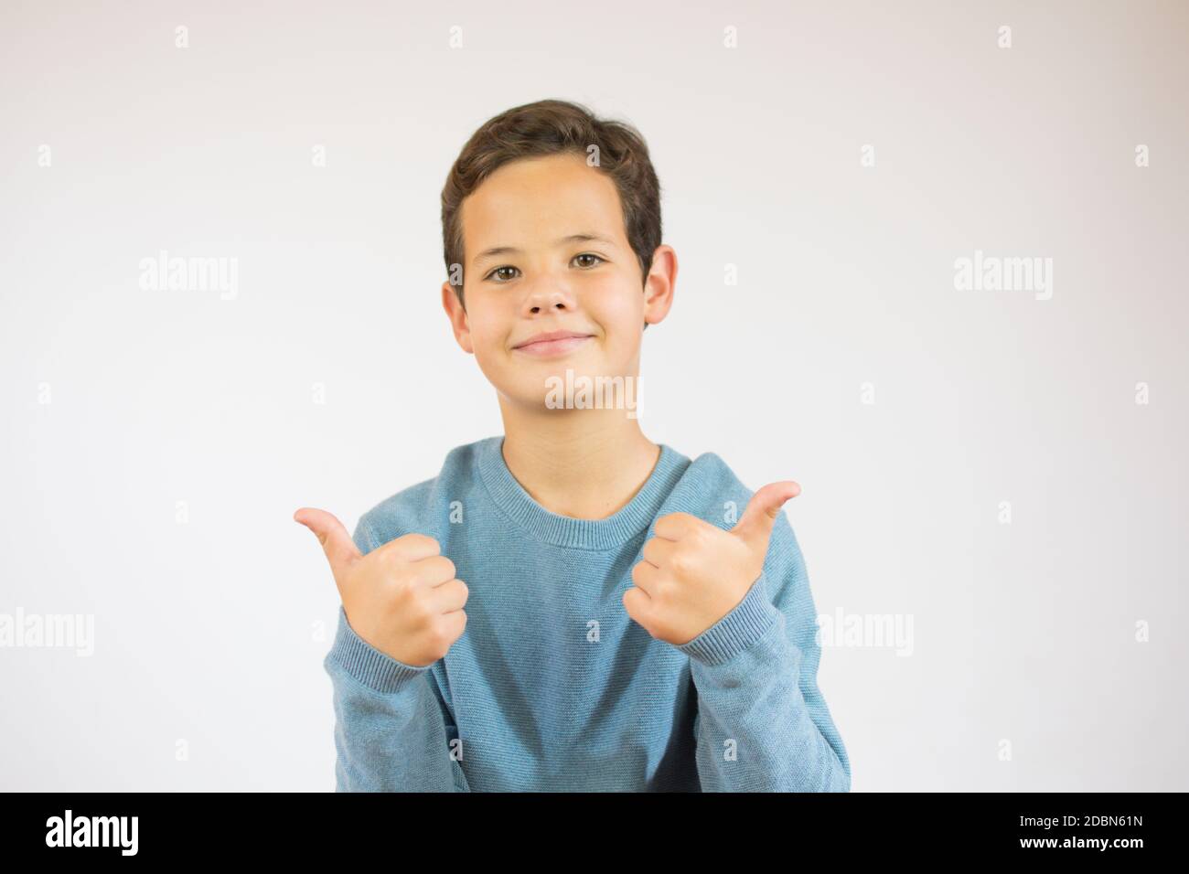 Portrait of a beautiful young boy smiling and showing thumbs up at ...
