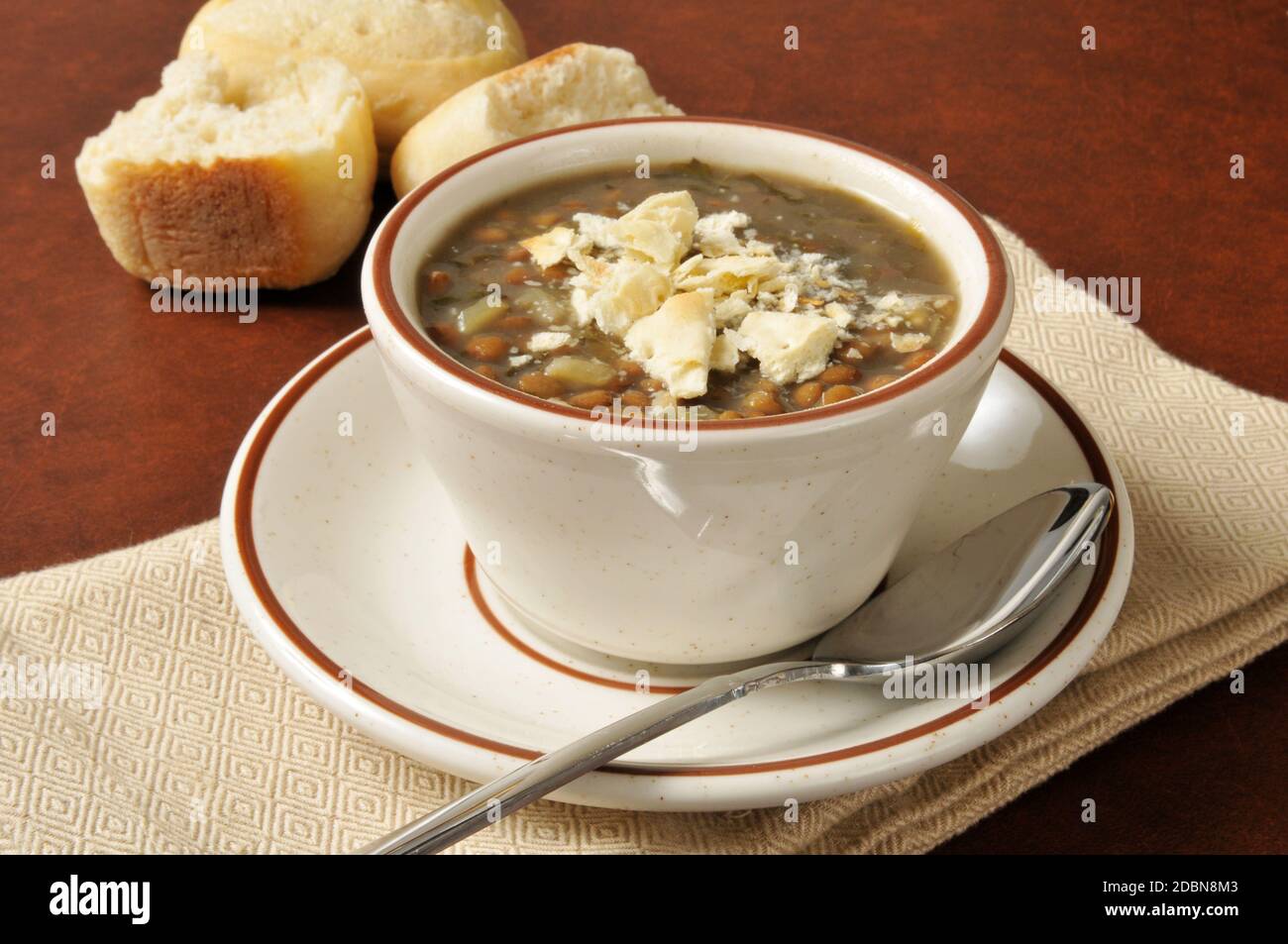 A cup of lentil soup with saltine crackers crumbled on top Stock Photo