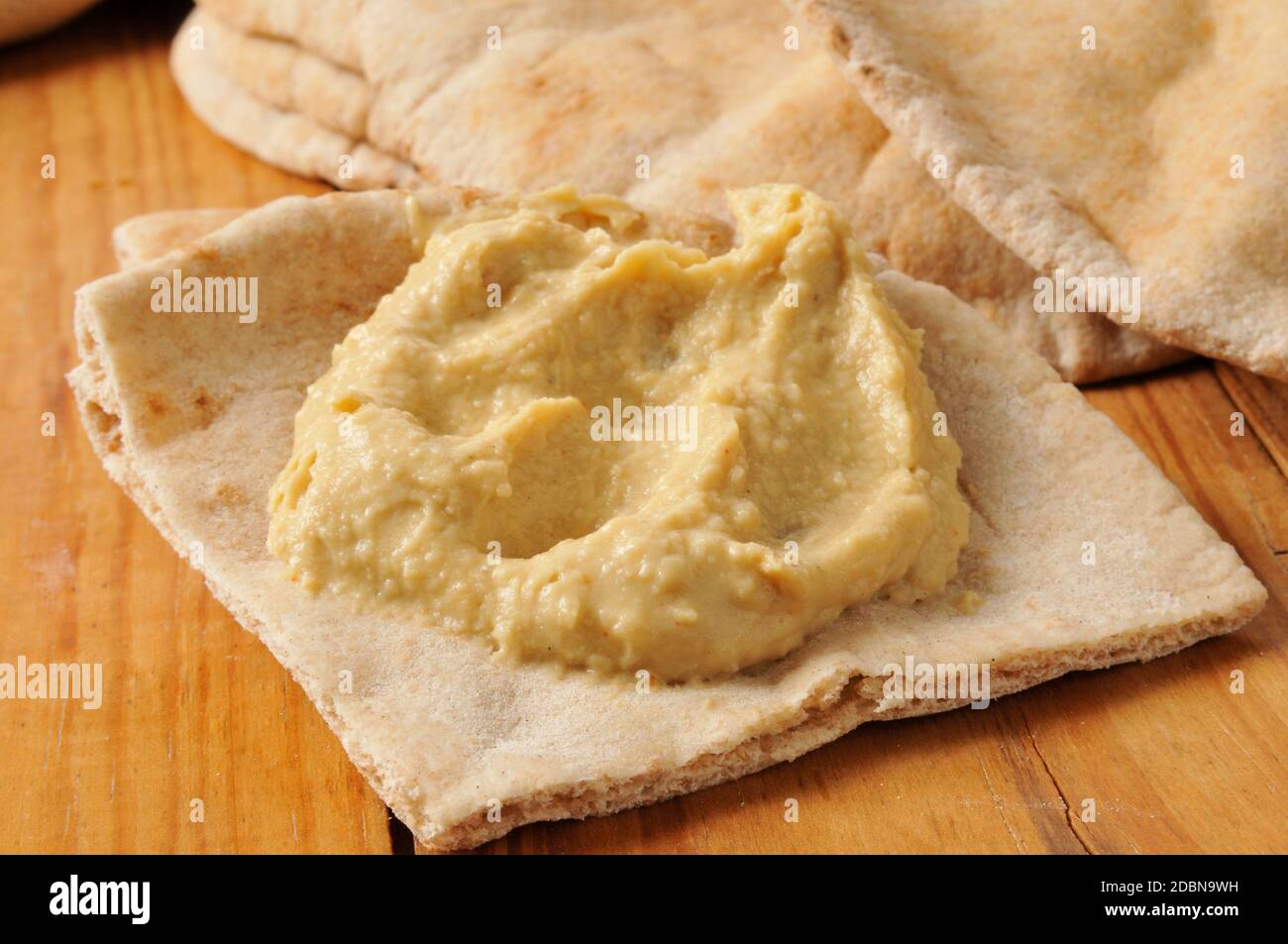 Garlic hummus on a wedge of pita bread on a rustic wood table Stock