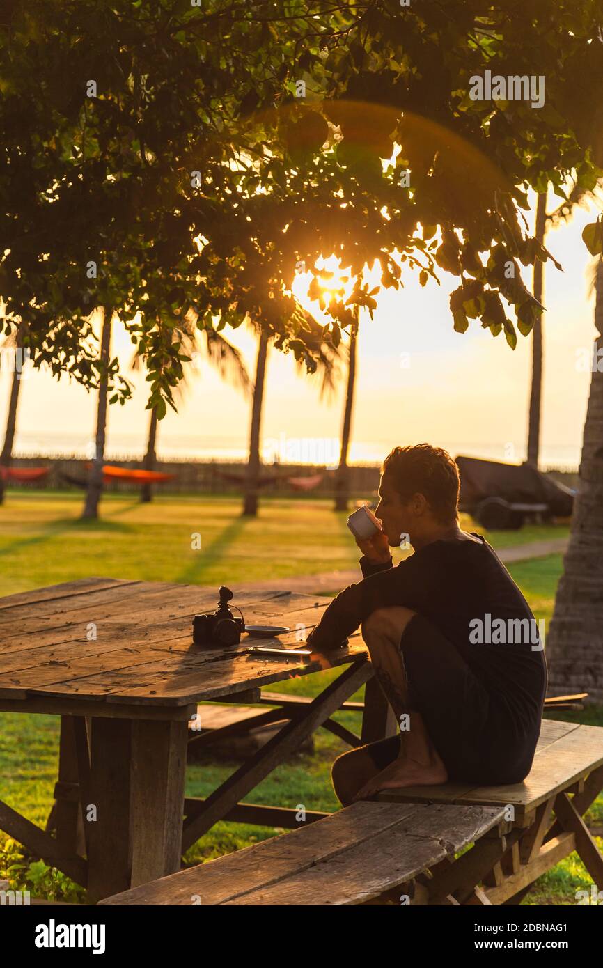 Young man drinking tea at outdoor table, Sumbawa, Indonesia Stock Photo