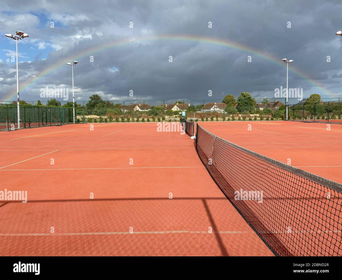 Clay tennis courts and rainbow, Ashford Tennis Club, Woodthorpe Road, Ashford, Surrey, England, United Kingdom Stock Photo