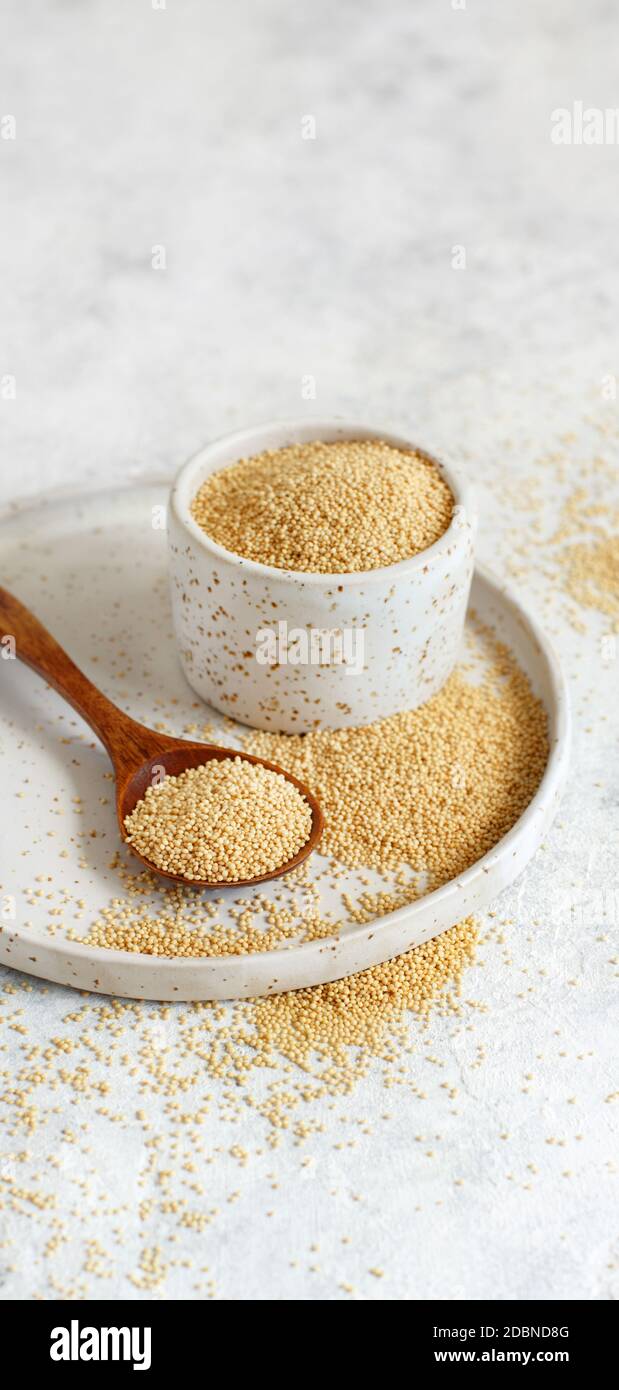 Bowl of Raw Amaranth Grain with a spoon close up on a white table Stock Photo