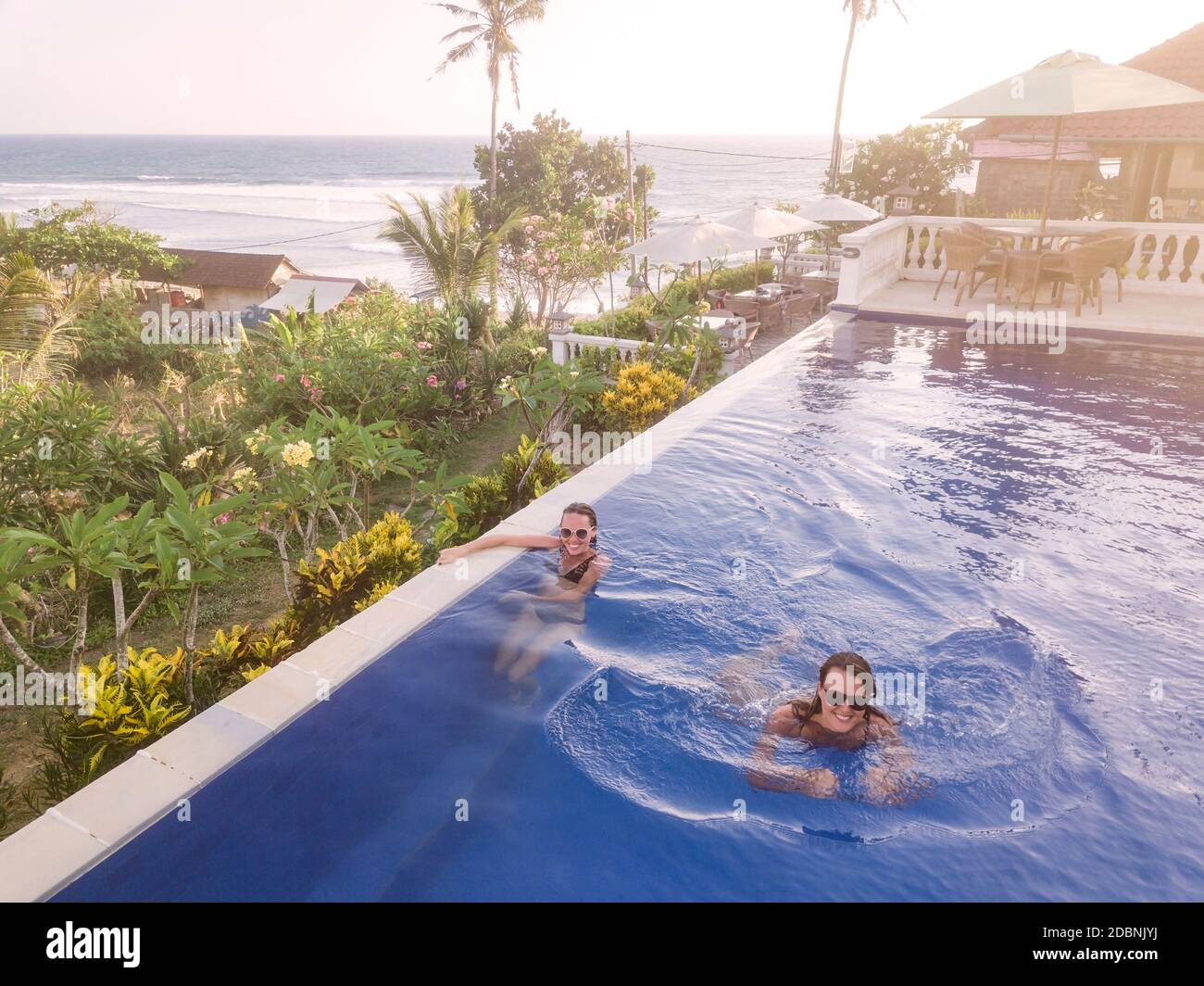Two women in swimming pool in hotel, Balian, Bali, Indonesia Stock Photo