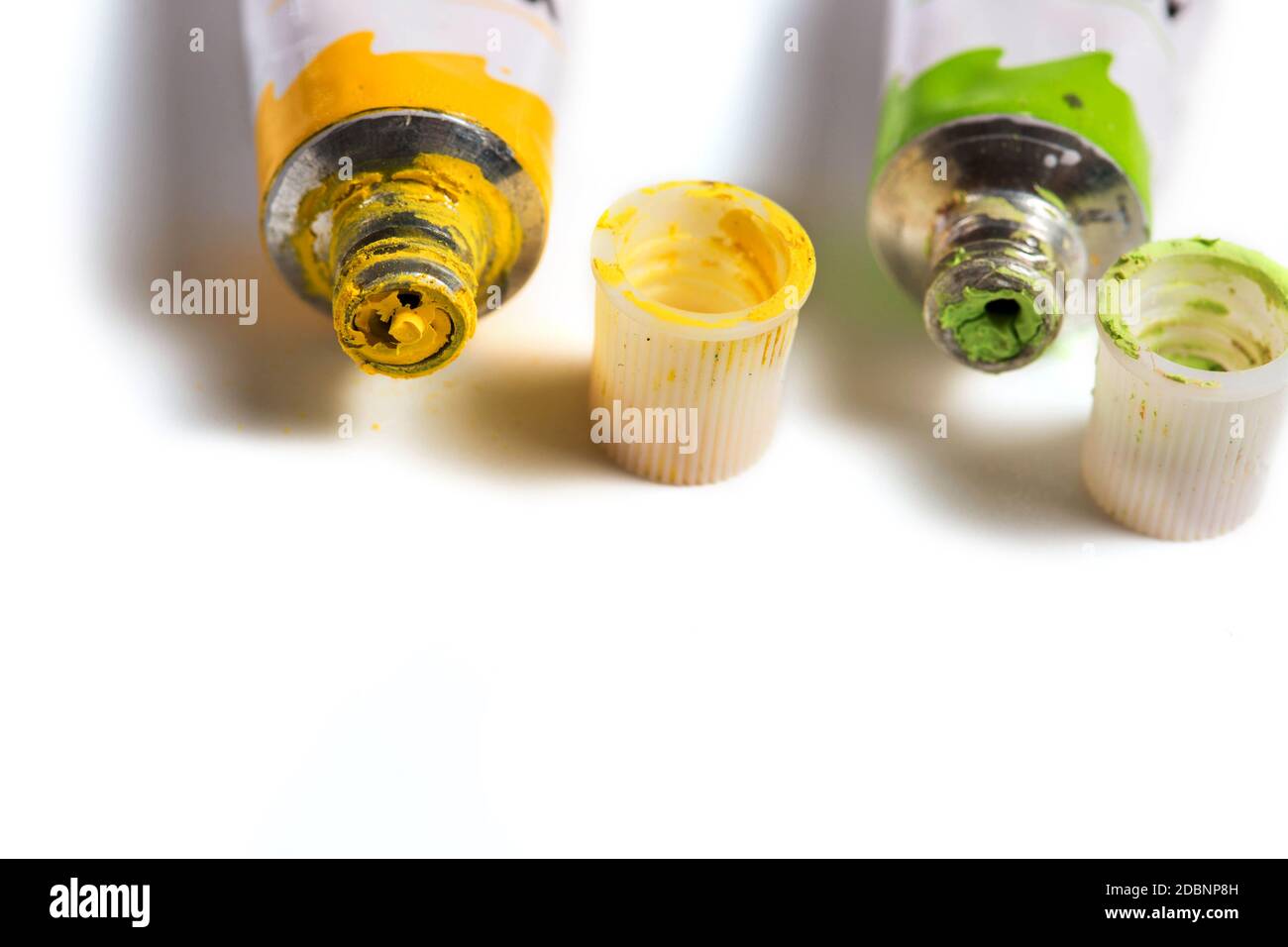 Dried green and yellow watercolor paint in a tube isolated on white