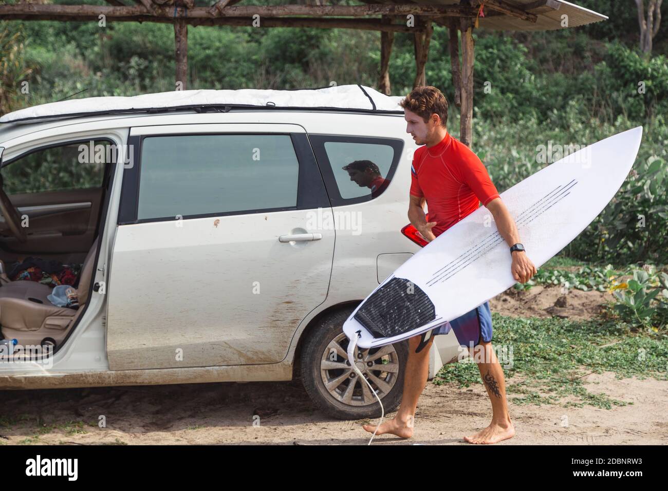 Surfer with surfboard near car,Ã‚Â Sumbawa, Indonesia Stock Photo