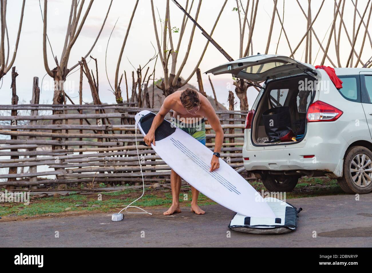 Surfer with surfboard near car,Ã‚Â Sumbawa, Indonesia Stock Photo