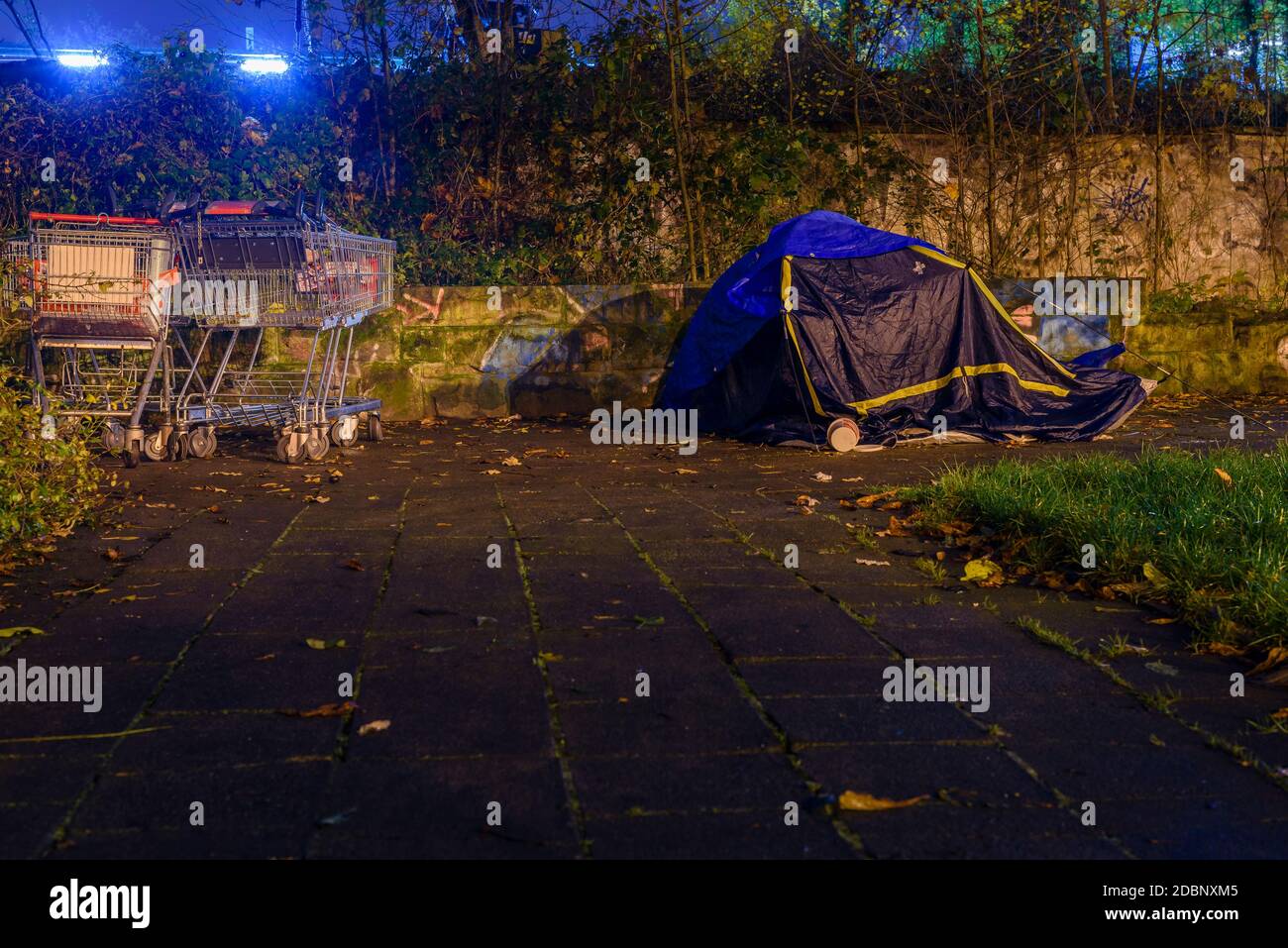 Tent of a homeless person in the city at night, shopping cart and a tent of a homeless person at night, rainy weather Stock Photo