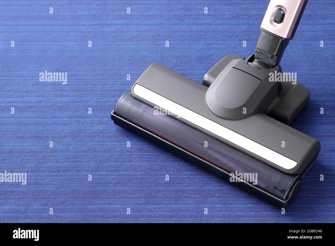 Head of modern vacuum cleaner on blue carpet background. Close up. Stock Photo