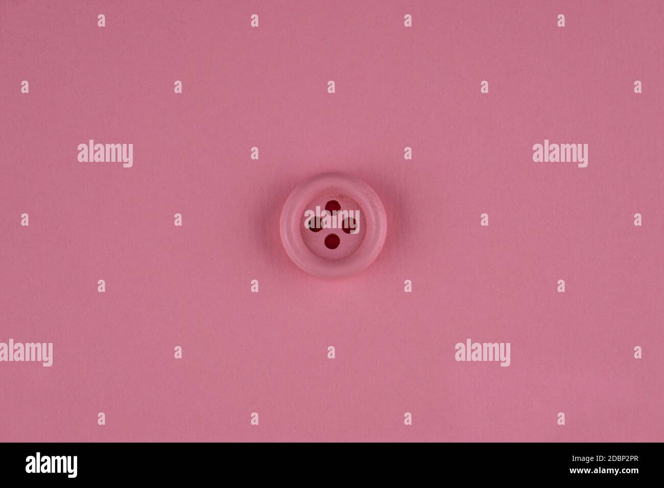 Minimal pink background with pink button in middle. Flat lay Stock Photo